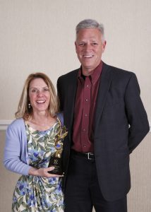 Woman and a man standing next to each other holding an award