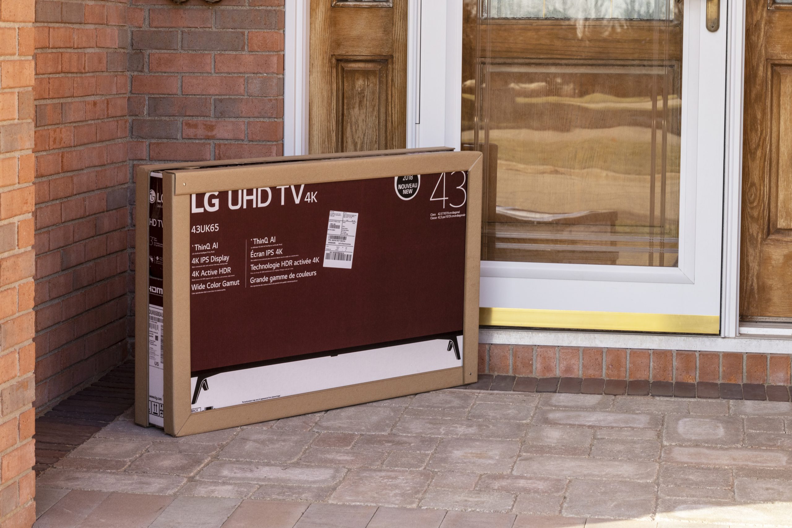 TV in a box sitting on a porch with protective coverings around the edges of the box